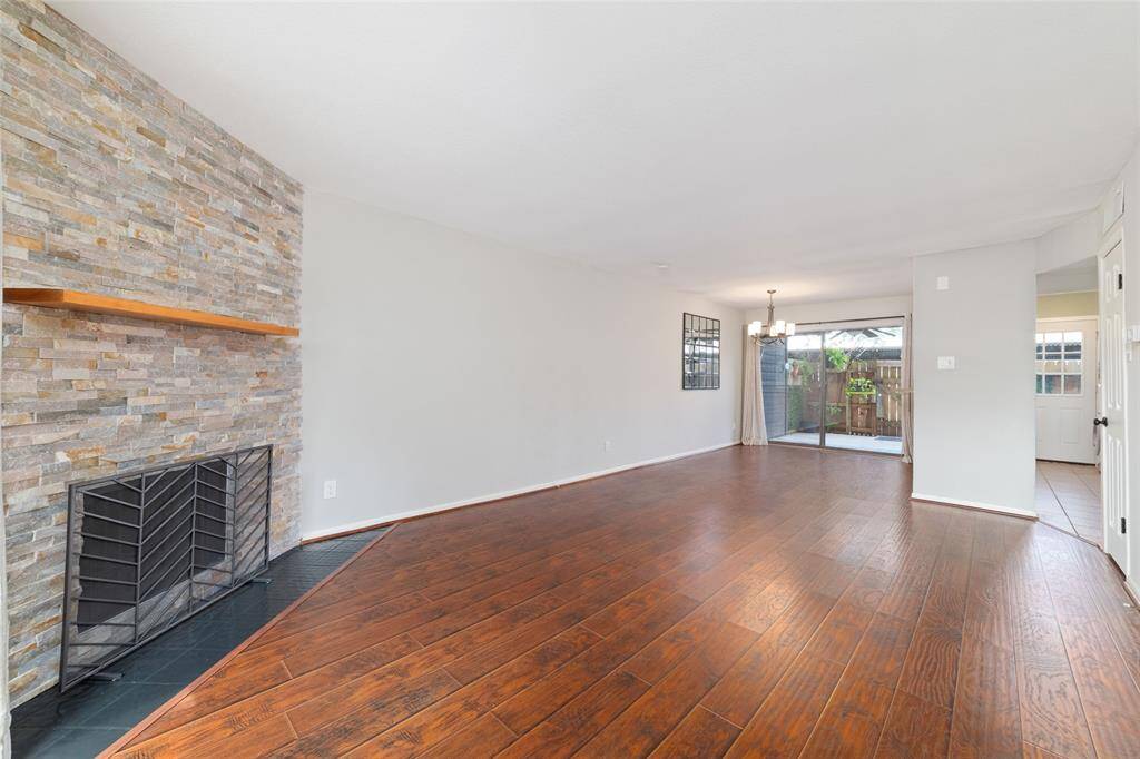 A bright living room featuring modern floors and a stylish stone fireplace, with sliding glass doors offering a view of the private patio!