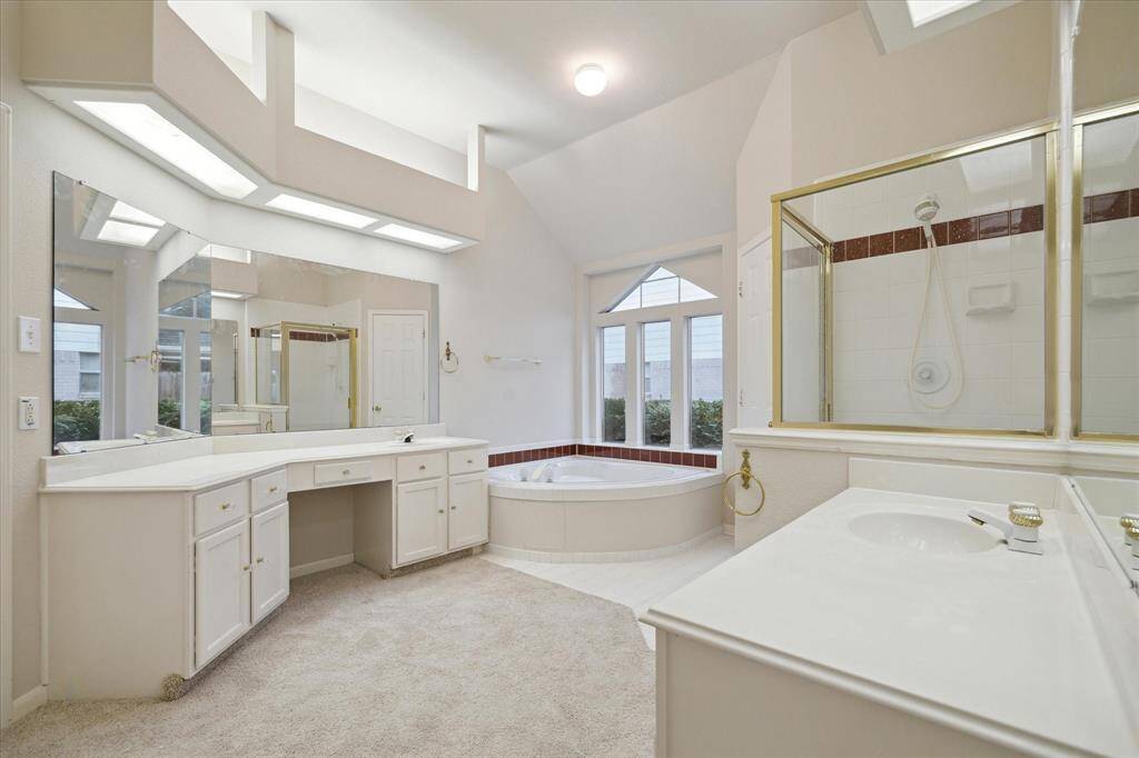 PRIMARY BATH WITH HIS AND HER VANITIES, CORNER SOAKING TUB AND WALK-IN SHOWER.
