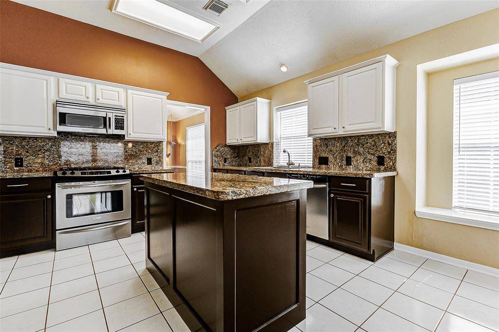 Beyond their practical function, the stainless steel gas range, microwave, and dishwasher contribute to the kitchen's polished look.