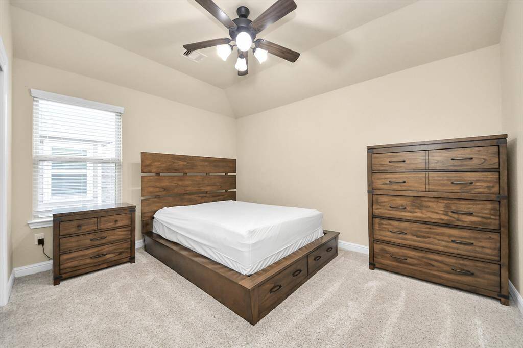 Bedroom #2 features a queen-sized bed with built-in storage, matching dressers, a ceiling fan and a large window for natural light.