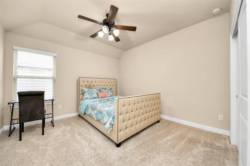 Bedroom #3 features a neutral color scheme with a plush carpet and a ceiling fan. It includes a comfortable bed with a tufted headboard, a desk by the window for natural light, and a spacious layout ideal for relaxation or work.