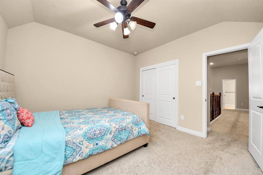 Bedroom #3 features a neutral color scheme with a plush carpet and a ceiling fan. It includes a comfortable bed with a tufted headboard, a desk by the window for natural light, and a spacious layout ideal for relaxation or work.