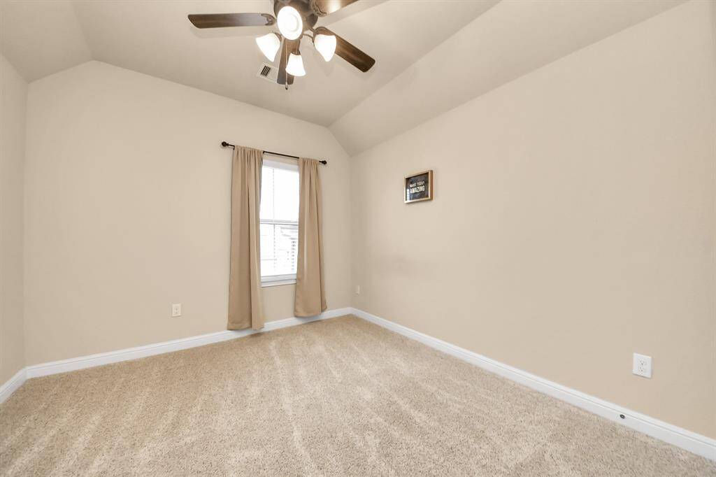 Bedroom #4 features neutral walls, plush carpeting, and a ceiling fan with lights. There is also a window with curtains that allows natural light, creating a cozy and inviting space ready for your personal touch.