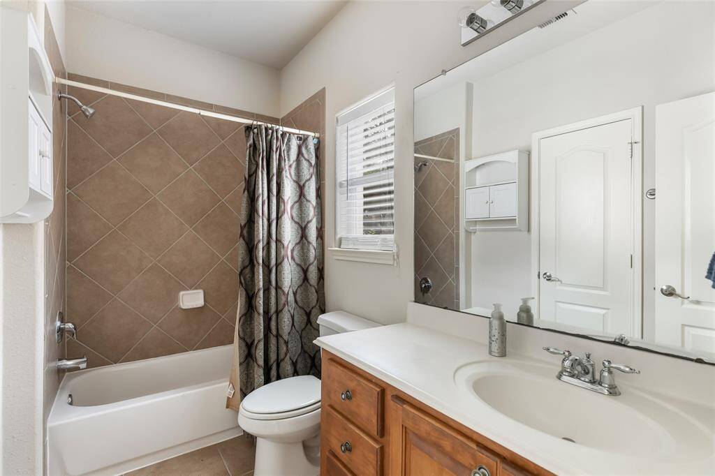 Bright and inviting second bathroom featuring elegant tile work, a spacious vanity, and a convenient shower-tub combination.