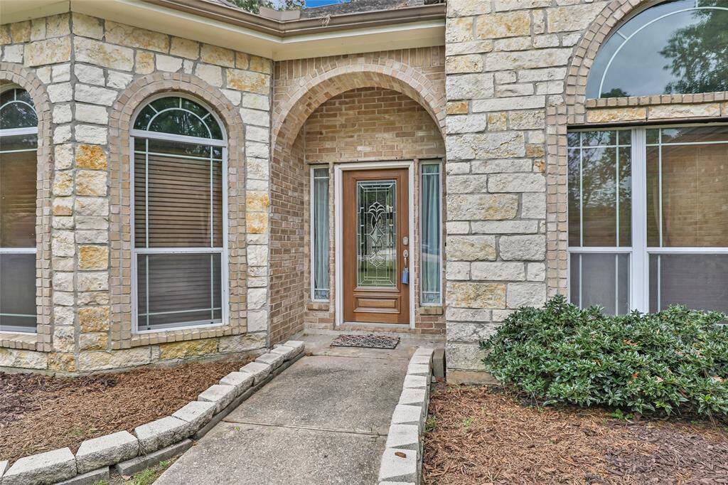 Welcoming stone entryway with elegant arch and charming front door, framed by large windows for abundant natural light.