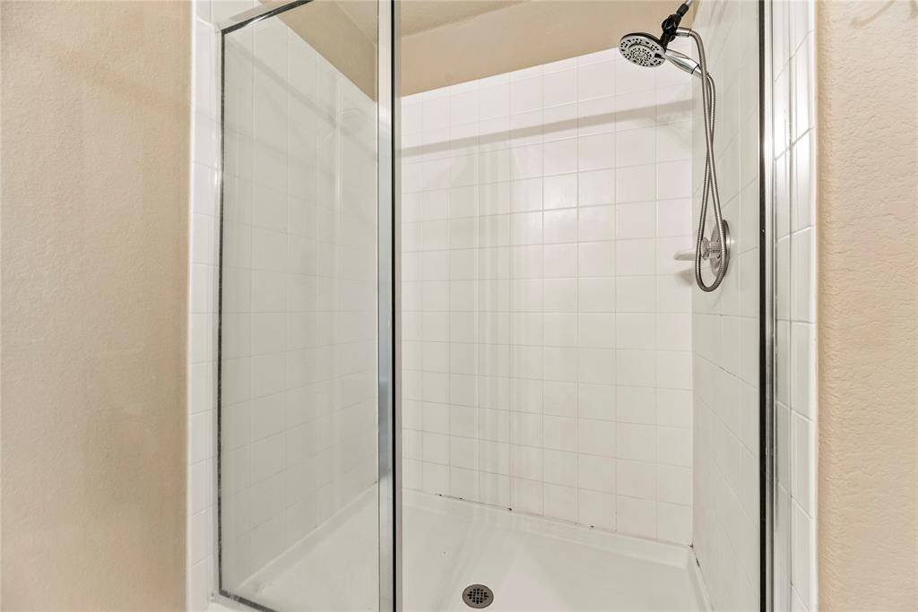 The expansive walk-in shower,  with beautiful tile and a sleek glass front, offers a luxurious escape for a quick rinse or a refreshing retreat.