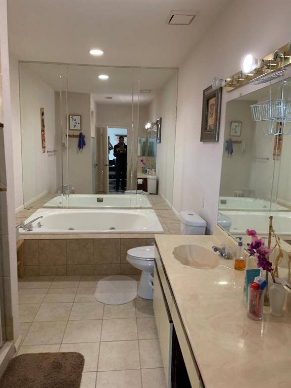 This bathroom provides a comfortable and functional space with a separate soaking tub and shower for relaxation, while the double vanity offers convenience with ample counter space for daily routines. The well-lit environment, enhanced by a large mirror, contributes to a bright and spacious feel.