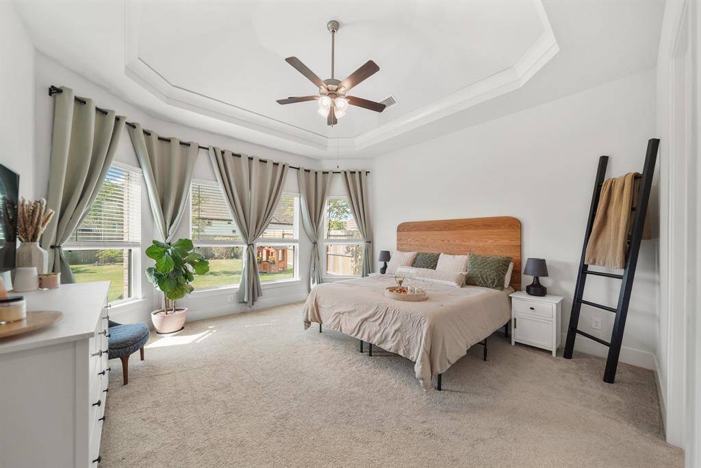 Spacious primary bedroom retreat with plush carpeting and tall windows.