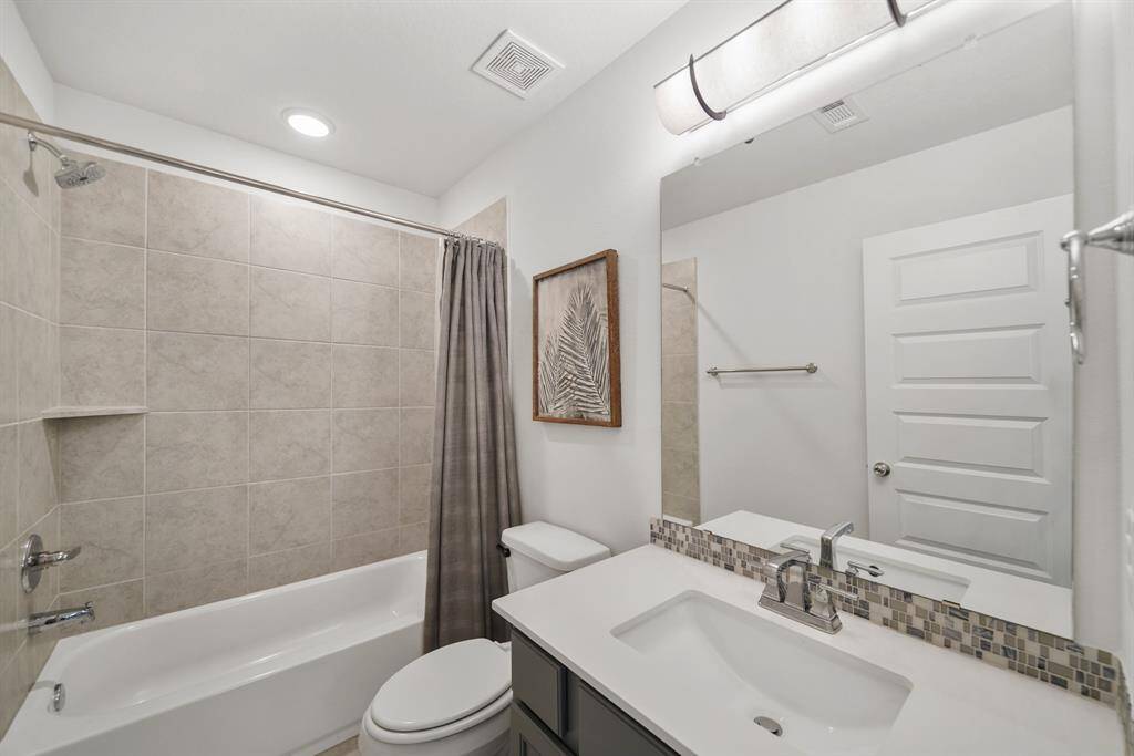 Secondary bath with sleek design elements, modern cabinetry, and a tub/shower combo for everyday function.
