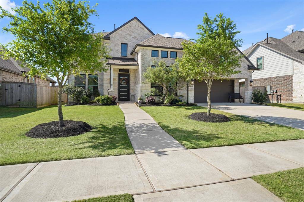 Front exterior view with manicured landscaping, upgraded light fixtures, and a charming covered entryway that sets the tone for luxury inside.