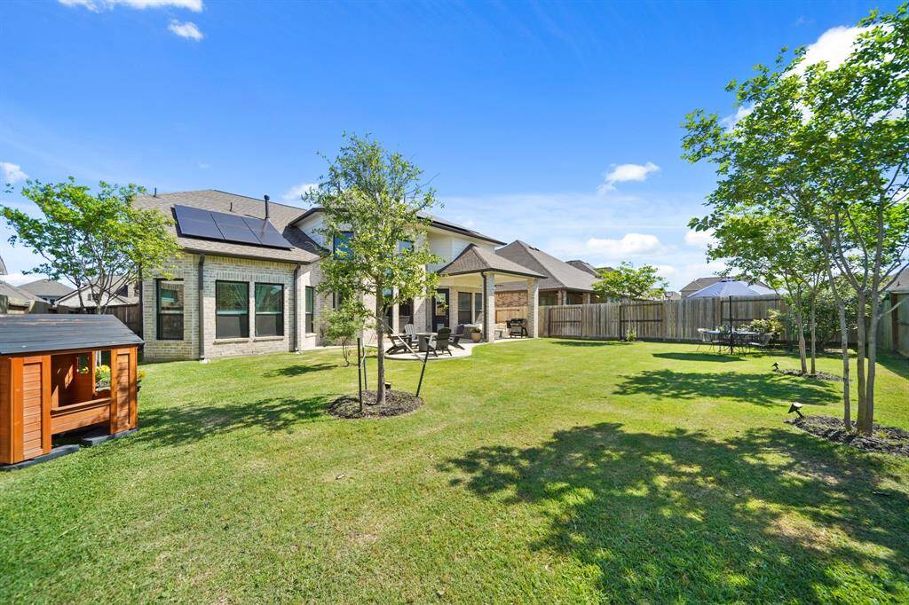 View of the fully fenced yard with mature grass and open sky—ideal for pets, kids, or weekend BBQs.