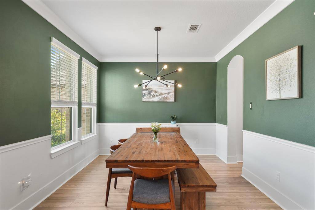 Spacious formal dining room with upgraded chandelier and detailed molding.
