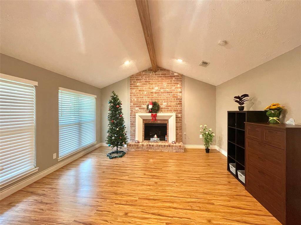 Family room showcases arched celling with wooden beam, large double pane windows for natural lighting