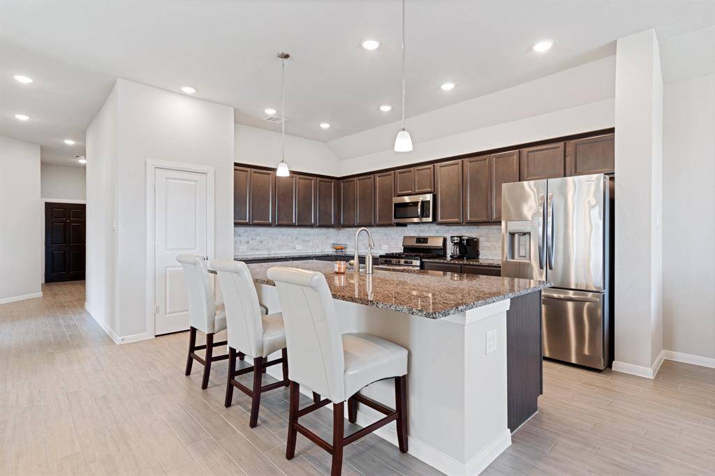 Beautiful kitchen with many dark cabinets, breakfast bar at the island and stainless steel appliances.