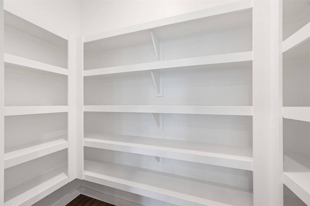 This is a spacious, well-lit pantry with multiple white shelves, perfect for organized storage.