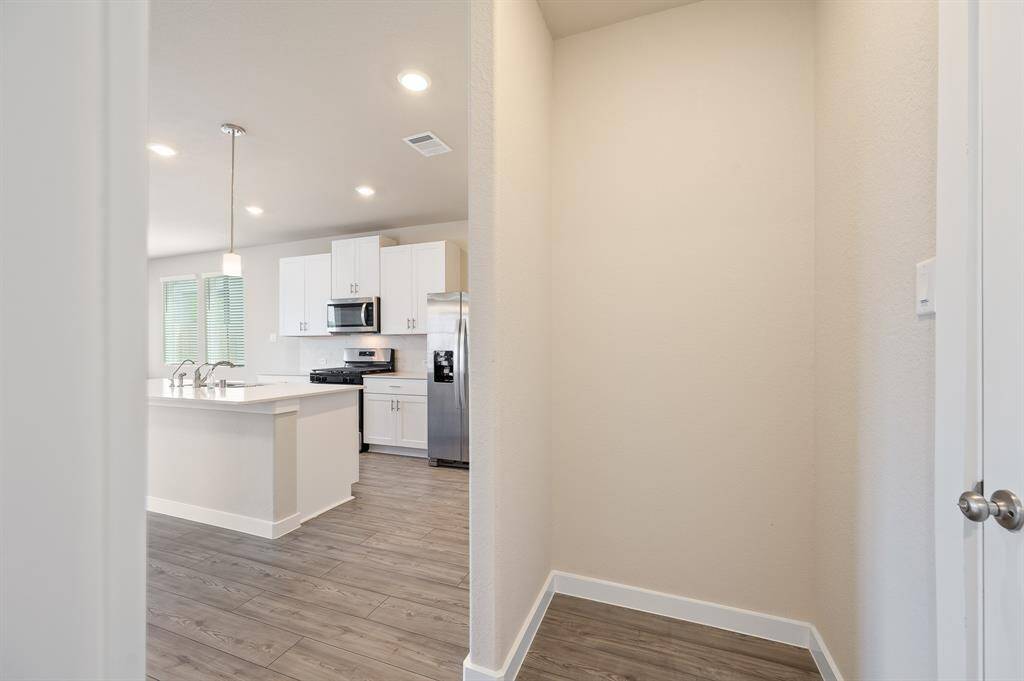 Bright, modern kitchen with white cabinets, stainless steel appliances, and a central island. The space features light wood flooring and ample natural light from large windows.