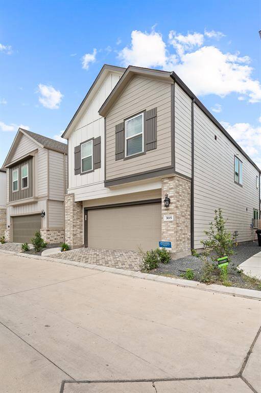 Discover this modern two-story home with a sleek neutral exterior, double garage, and charming brick accents. Located in a pristine neighborhood, it features a paved driveway and tasteful landscaping with shrubs.