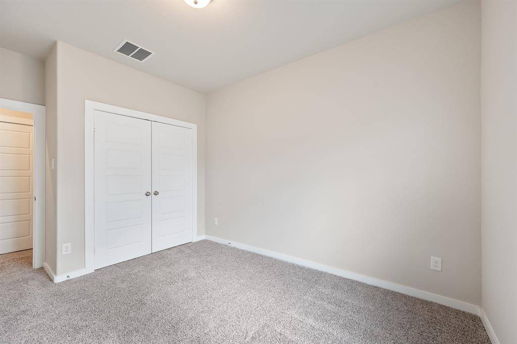This room features neutral walls and carpet, a double-door closet, and a simple light fixture, offering a clean and versatile space ready for personalization.