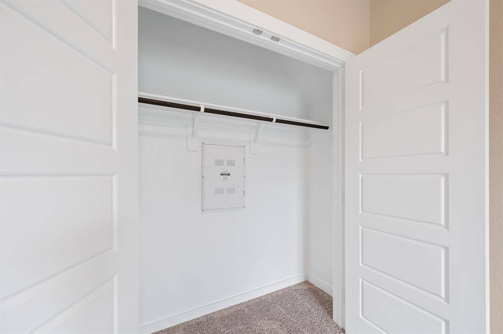 This photo shows a compact, freshly painted closet with double doors, featuring a built-in shelf and hanging rod, ideal for organizing clothes and accessories. There's also an access panel on the back wall, likely for utilities.