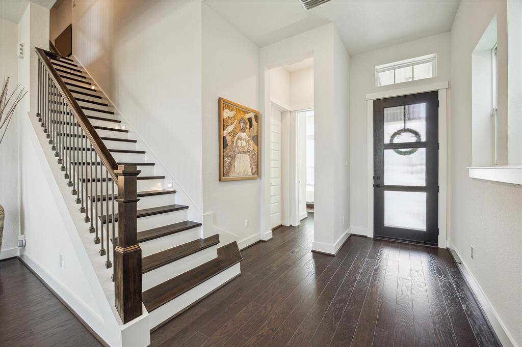 Inviting entry showing access to downstairs bedroom and stairway with wood treads and stair lighting.