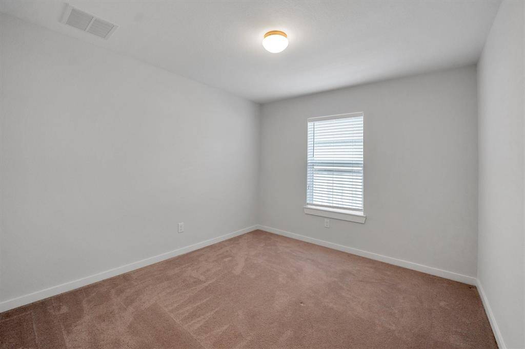 This is a secondary, with neutral colors and carpet, featuring a window with blinds that allows natural light to filter in.