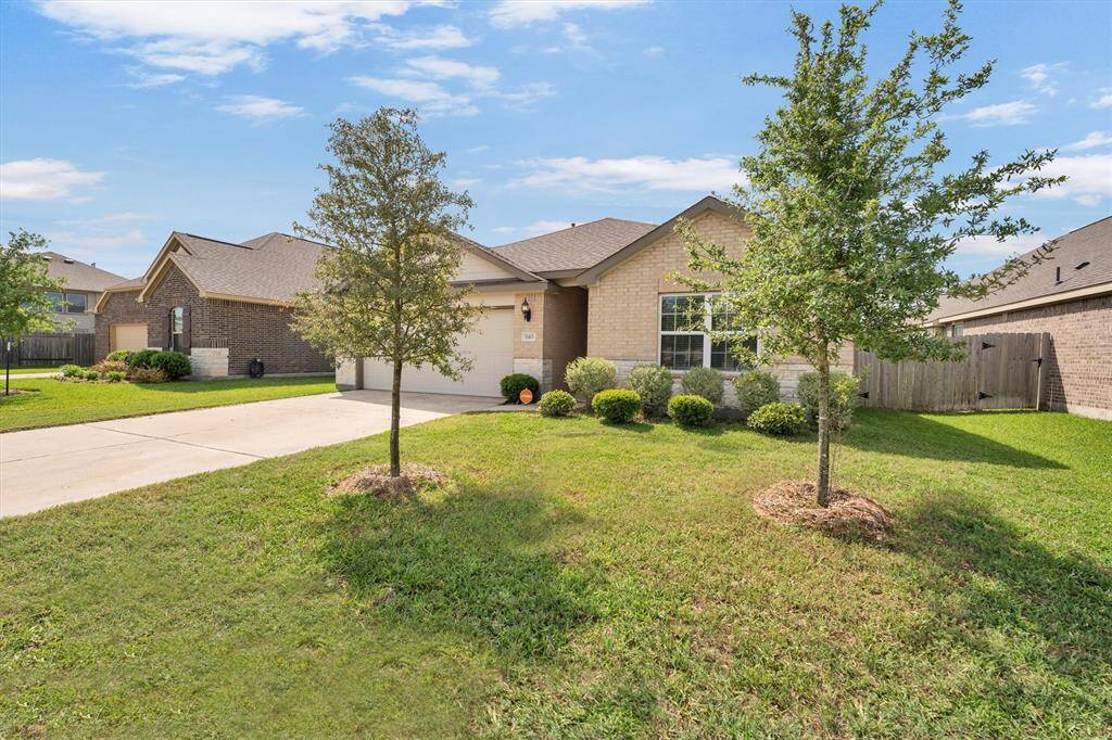 This photo features a single-story house with a two-car garage, neatly landscaped front yard, and concrete driveway. It's situated in a residential neighborhood with similar homes. The property is highlighted, showing its boundaries clearly.
