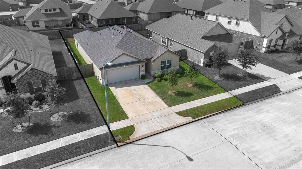 This photo showcases a charming single-story brick home with a well-maintained front yard, featuring two young trees and manicured shrubs. The property includes a driveway leading to an attached garage, set in a quiet suburban neighborhood.