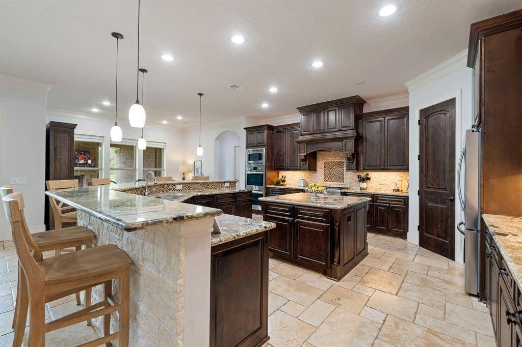 Cooking will never feel like a chore in this large and exquisite Kitchen! This Kitchen meticulously marries elegance, with form and function. The warm walnut-colored cabinets are counterbalanced with the rough-edged, cream-colored, brick backsplash.