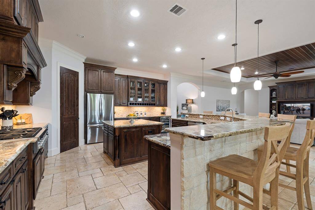Notice how the stately cabinets perfectly play off the wood paneled ceiling in the Living Room just beyond. There is that consistency again we were talking about. The Kitchen Island adds additional counter space for effortless prep work, and also boasts electrical outlets and an abundance of underneath storage.