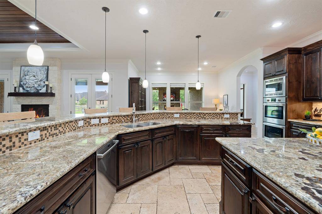 Four pendant lights illuminate the Breakfast Bar and expansive countertop space. The undermount, dual-basin, stainless steel sink comes equipped with a pull-down faucet and soap dispenser.
