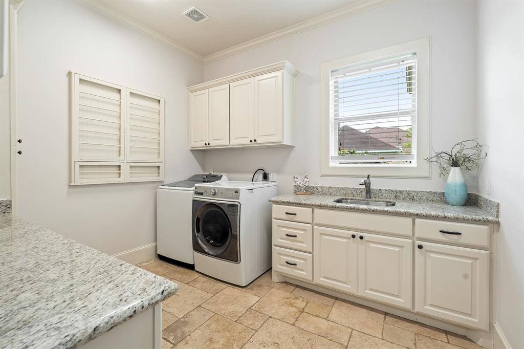 This spacious Laundry Room will make it easy to fight tough stains and sort multiple loads of laundry. The space comes equipped with an undermount, stainless steel sink, granite countertop, under and above cabinet storage, as well as a built-in, drop-down storage rack. The side-facing window adds natural light and a pretty view.