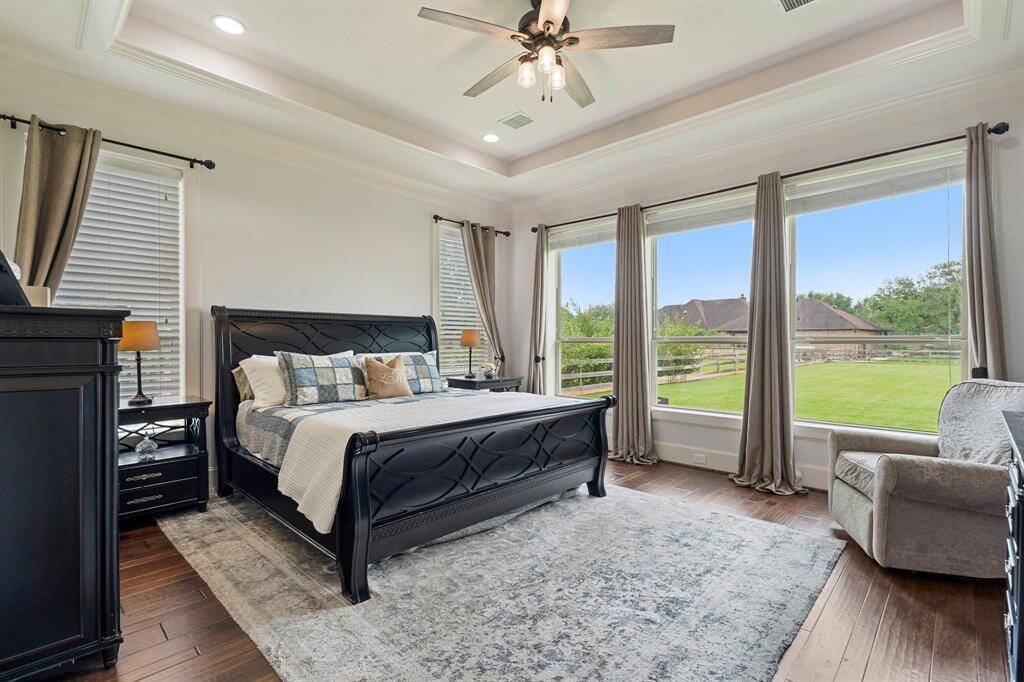 Serenity can be found in this impressive Primary Suite. Five large windows welcome in the desirable natural light, while also providing a calming pastoral view of the Back and Side Yards. Warm and rich wood floor dresses up the space, making the white baseboards and crown molding pop.