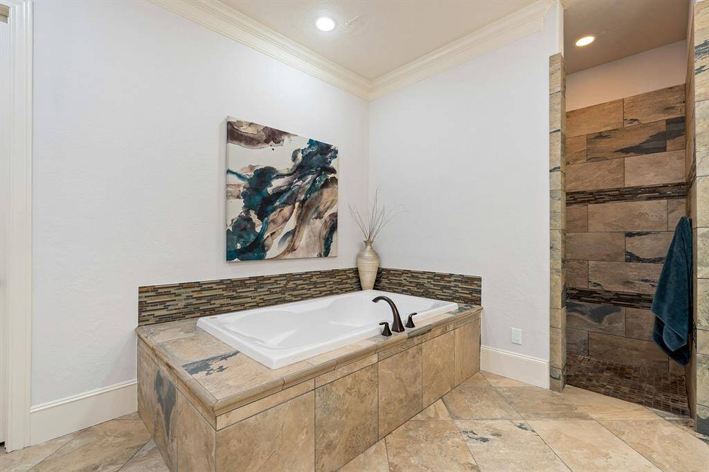 Wash away the stress of the day in this extra-large, soaker tub with tile surround. Doors just out of view lead to a water closet, linen storage, and to the walk-in closet.