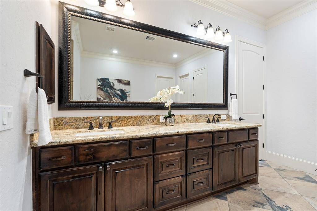 This spa-like Primary Bath is equipped with two undermount sinks, a granite countertop, a custom-framed mirror, and an abundance of built-in storage.