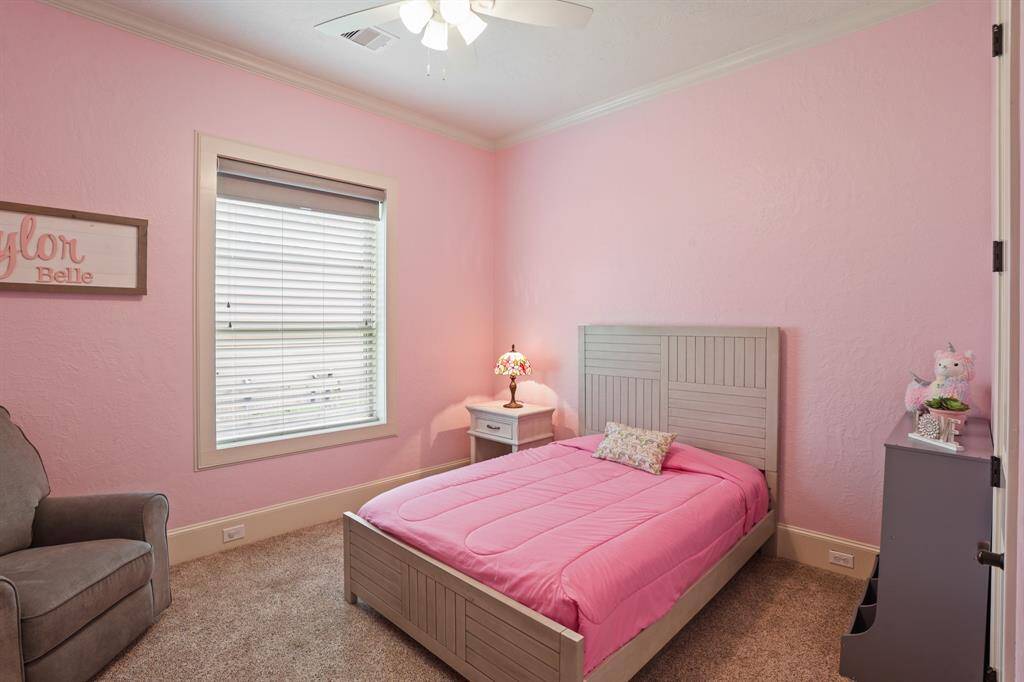 This Secondary Bedroom includes plush carpeting, crown molding, a 5-blade ceiling fan, and walk-in closet. It shares the full bath next-door with the fourth Secondary Bedroom down the hall.