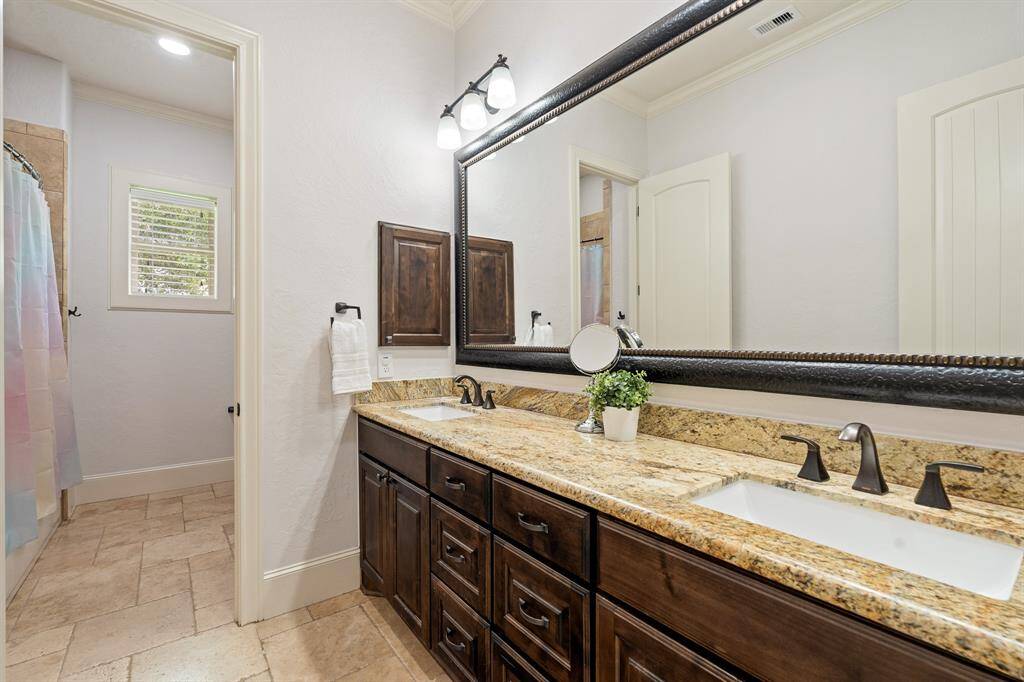 The second and third Secondary Bedrooms share this spacious bathroom equipped with dual undermount sinks, granite countertop, framed mirror, medicine cabinet, and tile flooring. Through the privacy of the second door, you will find a linen closet, toilet, and shower/tub combo that features an extra-large storage cubby.