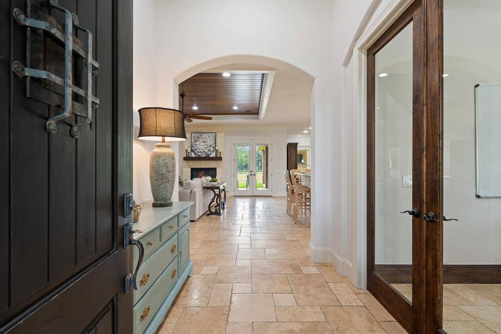 Upon entering the home, friends and family are greeted by a warm and inviting color pallet, high-end Versailles patterned tumbled Travertine flooring, and an elegant arched walkway. The eyes are immediately drawn toward the glass-paned double doors at the back of the home, and the picturesque views that await.