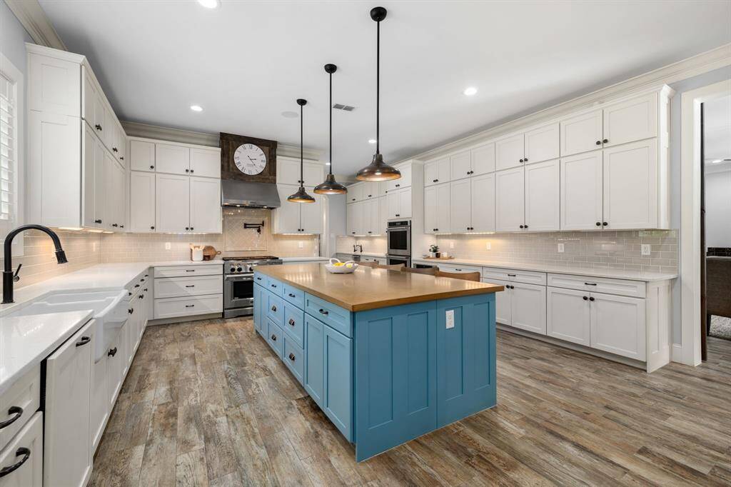 Local artisan handcrafted concrete old penny stained island counter top, hand crafted copper pendant lights from Bevolo in New Orleans. Island is painted an attractive turquoise blue giving vibrant contrasting color to the open kitchen and features cabinetry all the way around.
