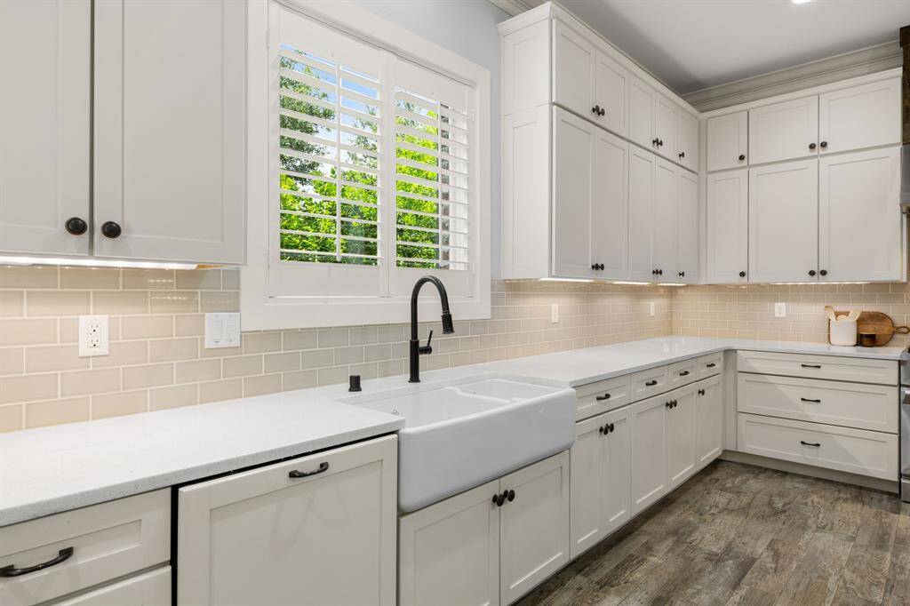 This stunning kitchen features attractive tile backsplash, custom panel built dishwasher and refrigerator, and a large window over the sink overlooking views of the property.