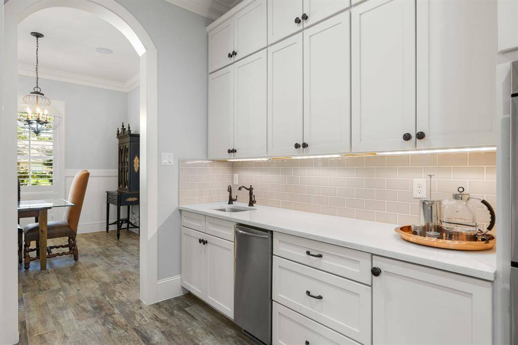 The scullery or butler off the kitchen was built with busy lifestyles in mind. This separate prep area features quartz counters, ice maker, extra cabinets and drawer space that will come in handy for holiday entertaining. To the left is a massive walk-in pantry for storing small appliances and stocking up on all the extras.