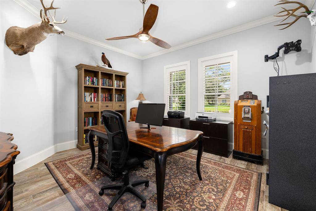 The study/6th bedroom is located at the front of the house overlooking the front porch and yard with plantation shutters and anchored with a modern style fan.