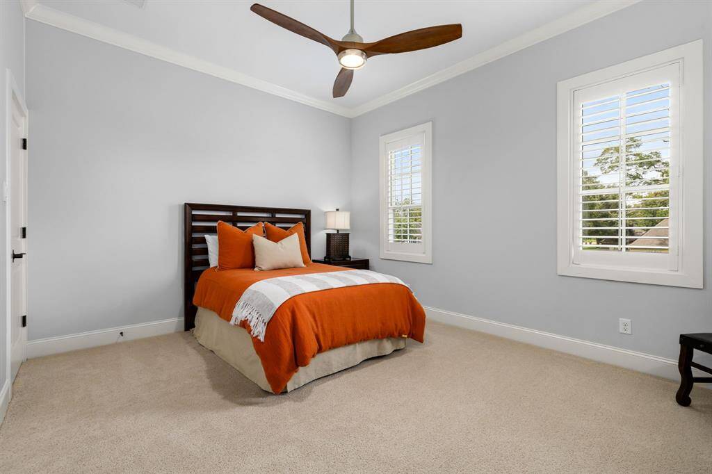 Secondary upstairs bedroom equipped with a fan, plantation shutters, walk-in closet and overlooking the front of the property.
