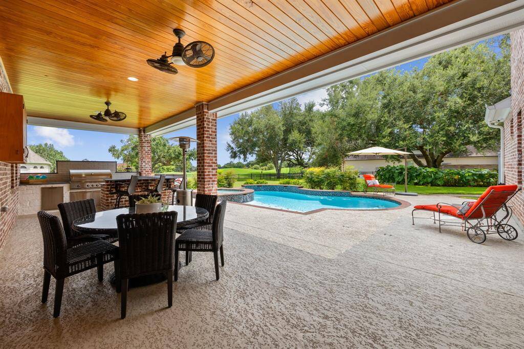 View of the pool. lush landscaping and mature oak trees, and the 16th hole of the Weston Lakes golf course.