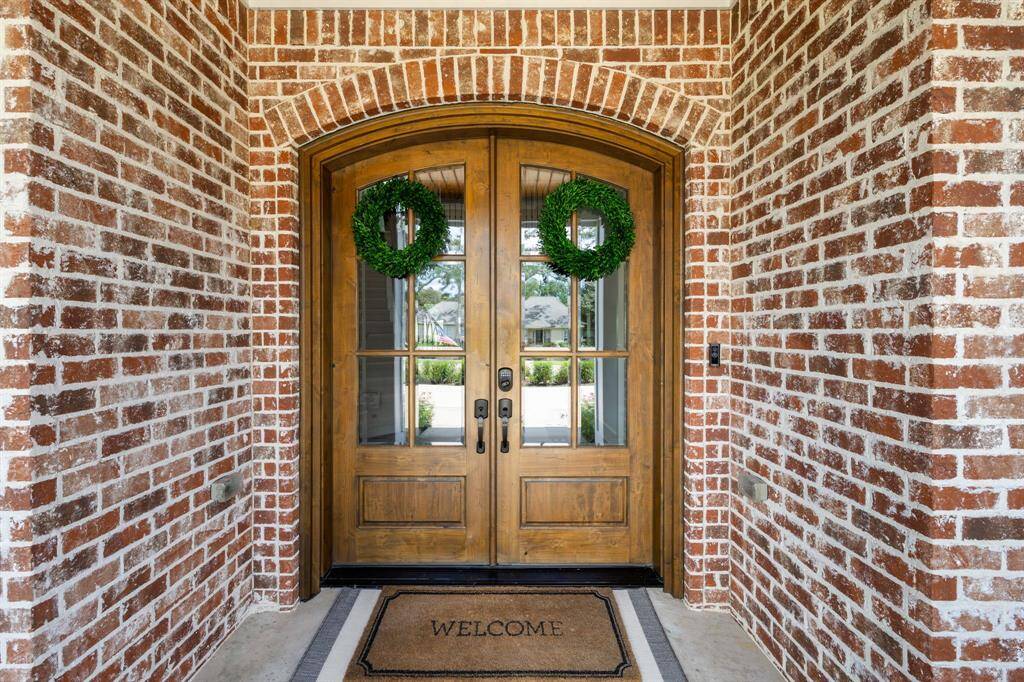 Full Texas ed brick entrance with gorgeous double knotty alder wood front entrance doors with beveled glass.