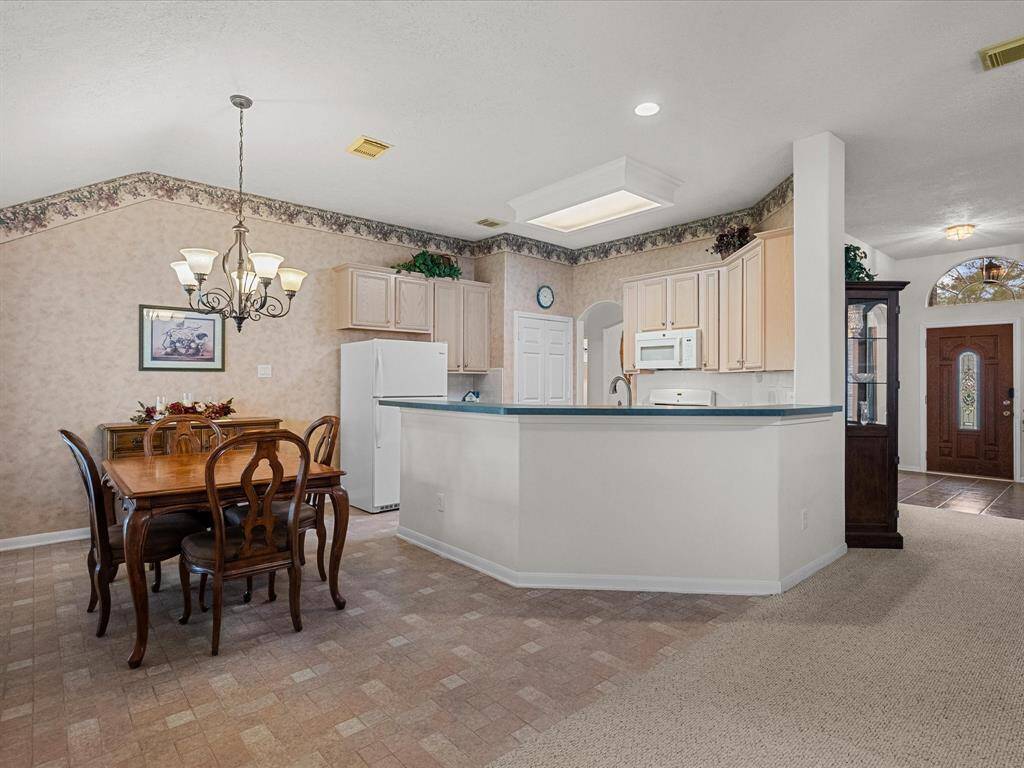 The combined kitchen and dining area offers a clear view of the family room, with a large window that frames the backyard and fills the space with natural light.