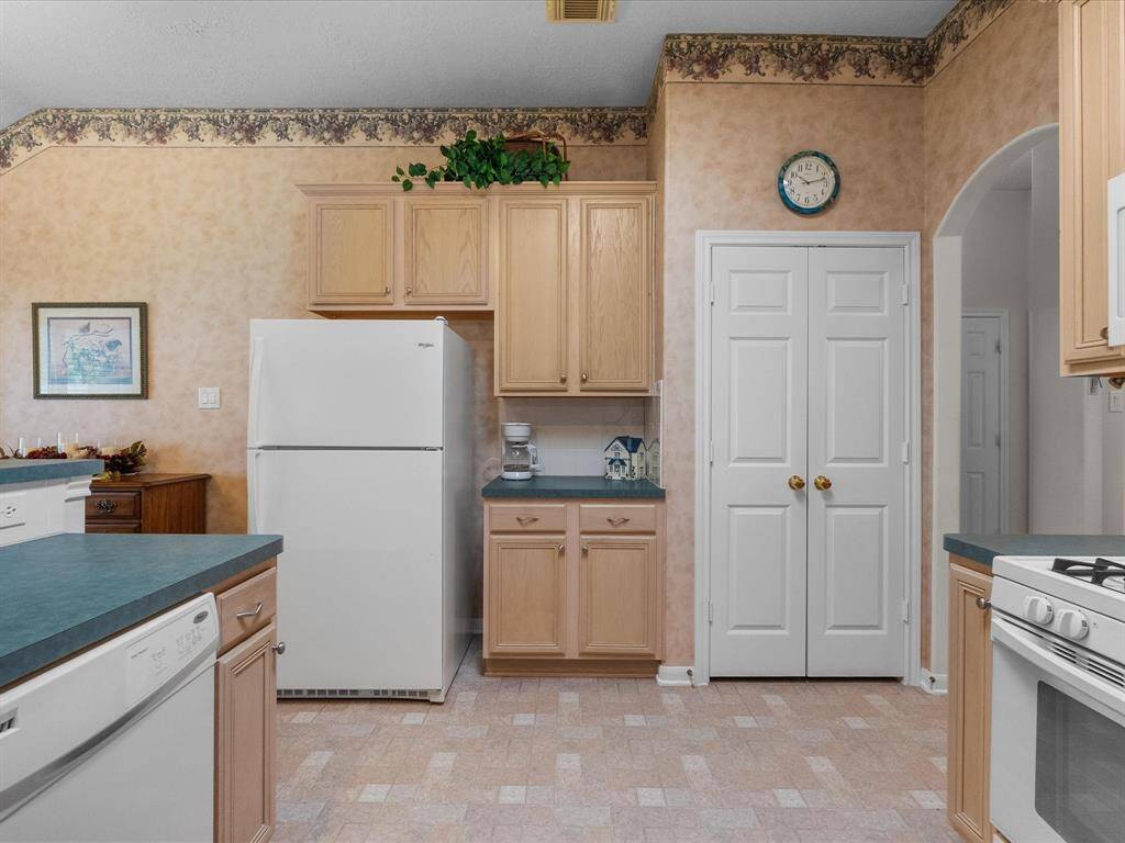 An adorable coffee bar is tucked perfectly between the refrigerator and pantry, creating a cozy and convenient spot to start your day.