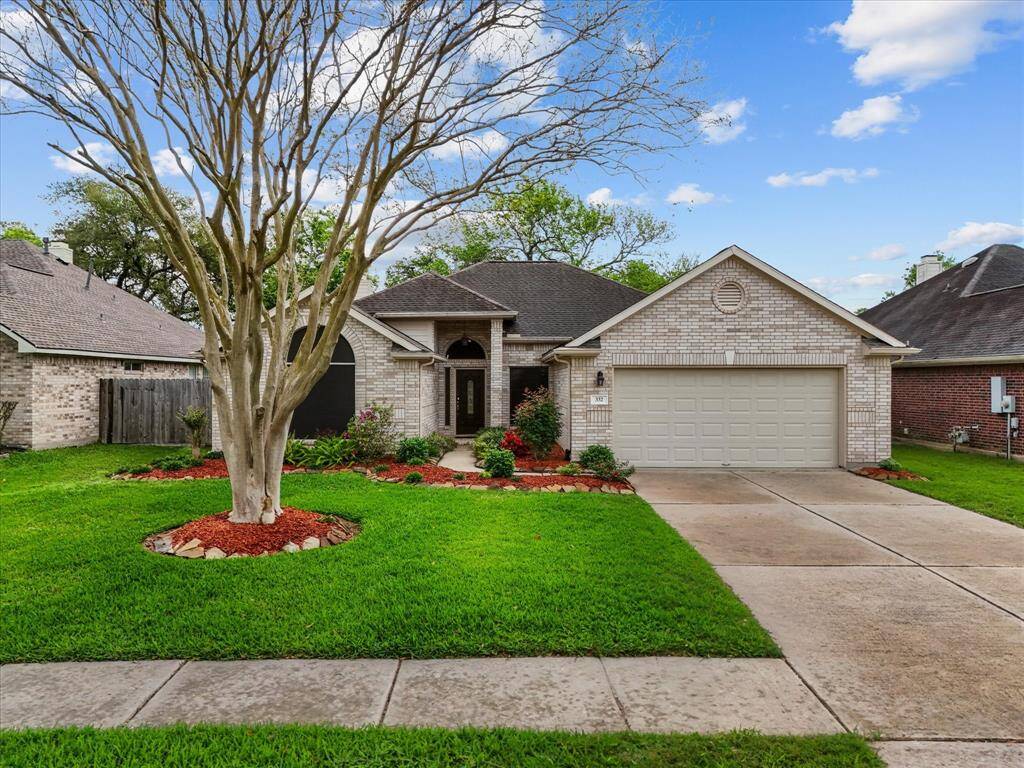 A charming walkway curves past a neatly manicured flowerbed, guiding the way to a welcoming front porch and entryway.