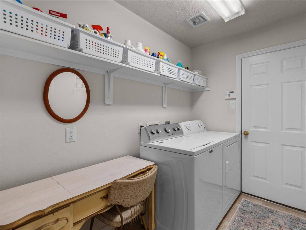 The large laundry room, located just off the garage, offers ample space along with built-in shelving for convenient storage and organization.