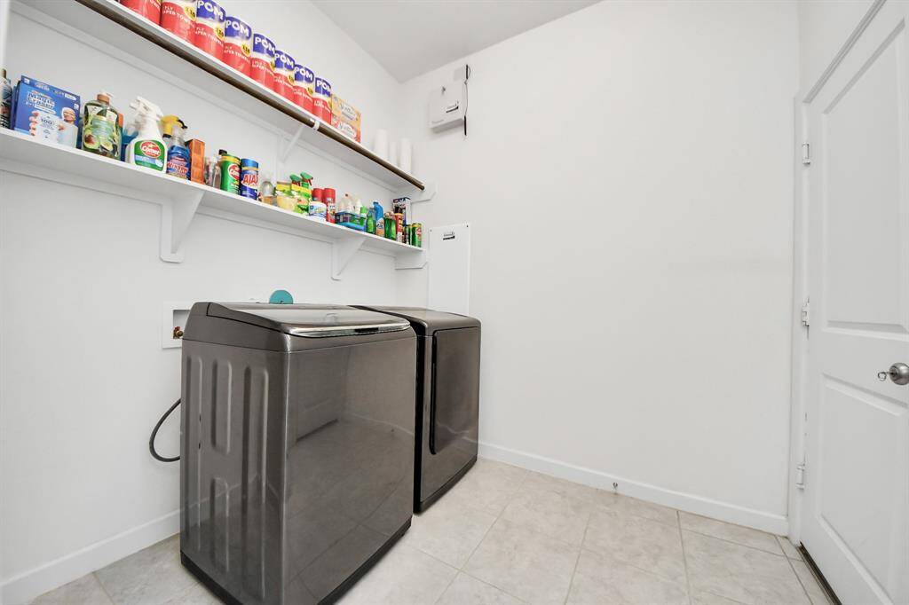 Enjoy the convenience of a spacious laundry room with ample shelving, perfectly situated off the garage.