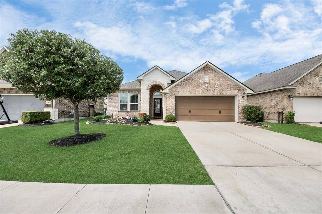 Charming single-story brick home with a two-car garage, beautifully landscaped front yard, and welcoming entry. The house features a well-maintained lawn and a cozy, inviting exterior illuminated under a picturesque twilight sky.